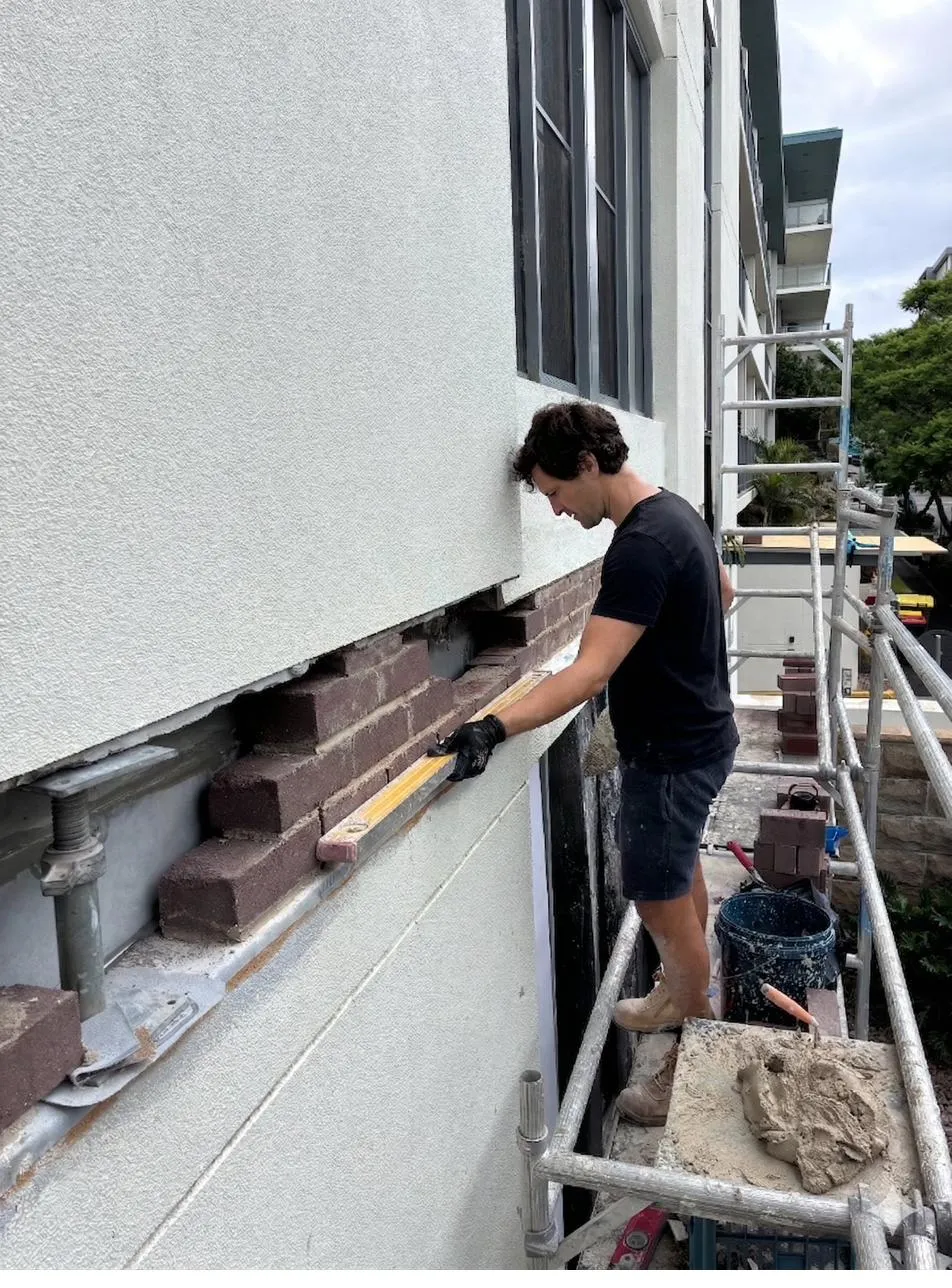 Ignacio inspecting brickwork with a spirit level on a Sydney remedial brickwork job
