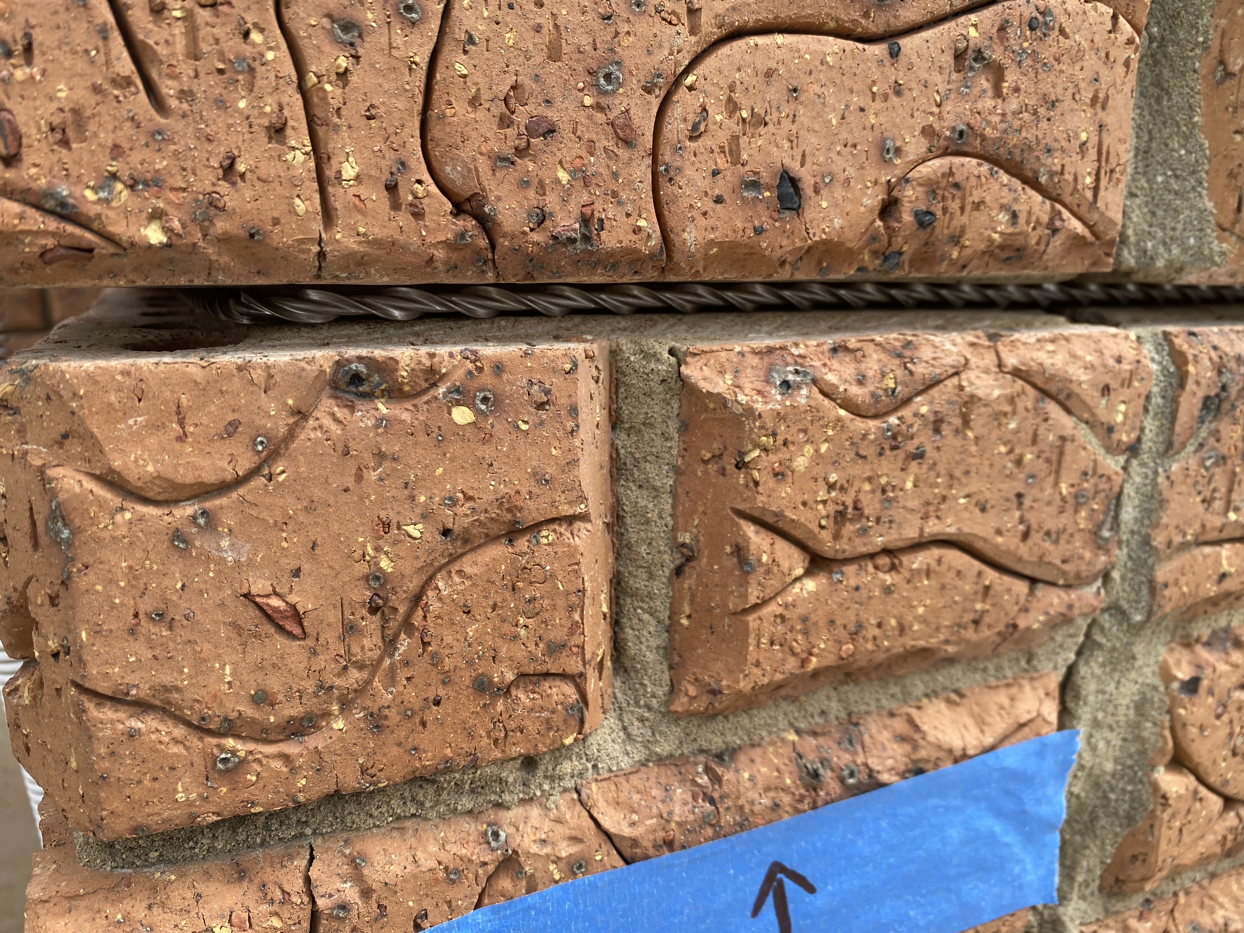 Detail of Helibar stitching with the helical bar bedded along the bed joint of textured red brickwork