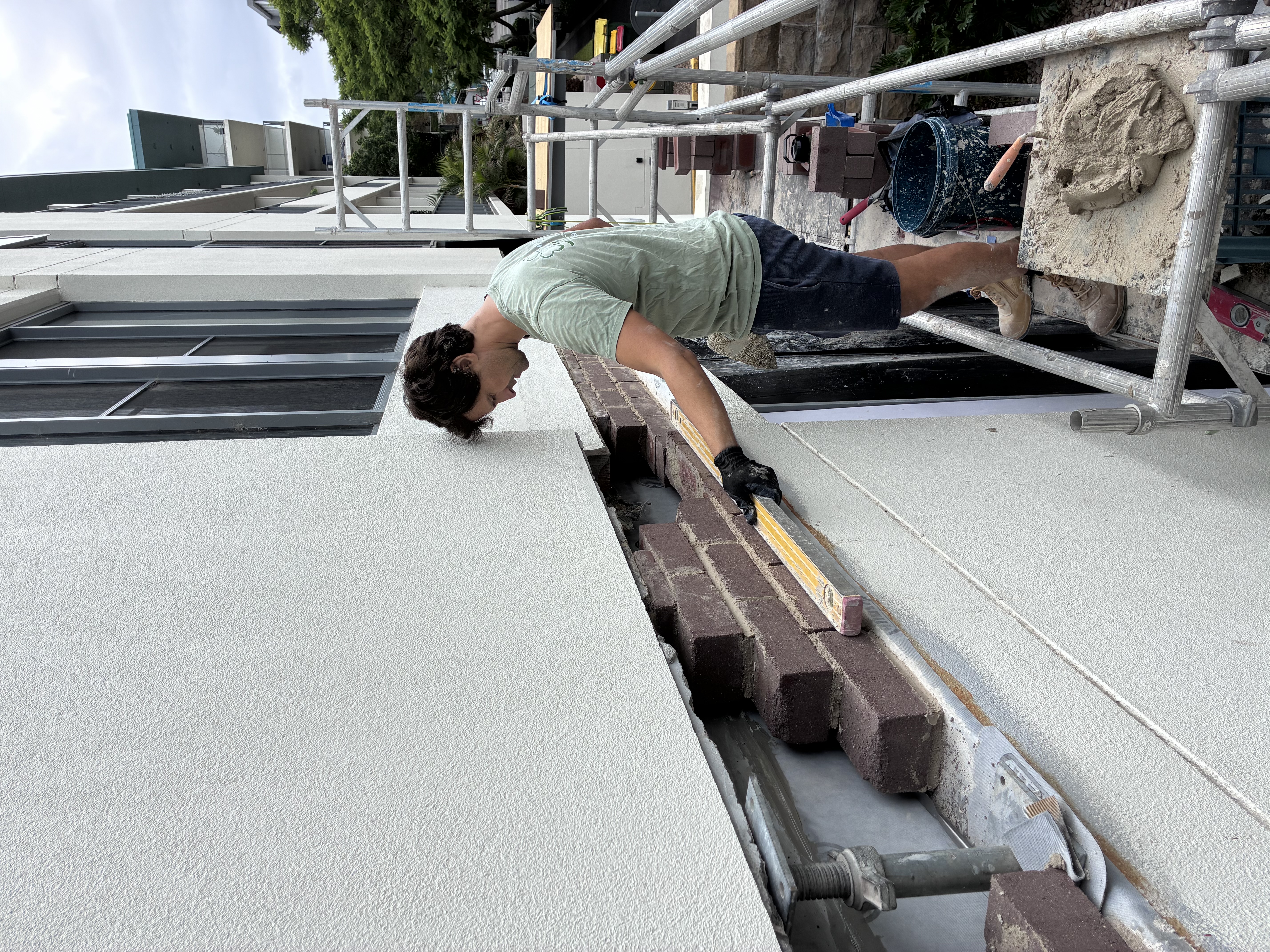 Setting fresh soldier course bricks along a parapet wall above a newly installed lintel