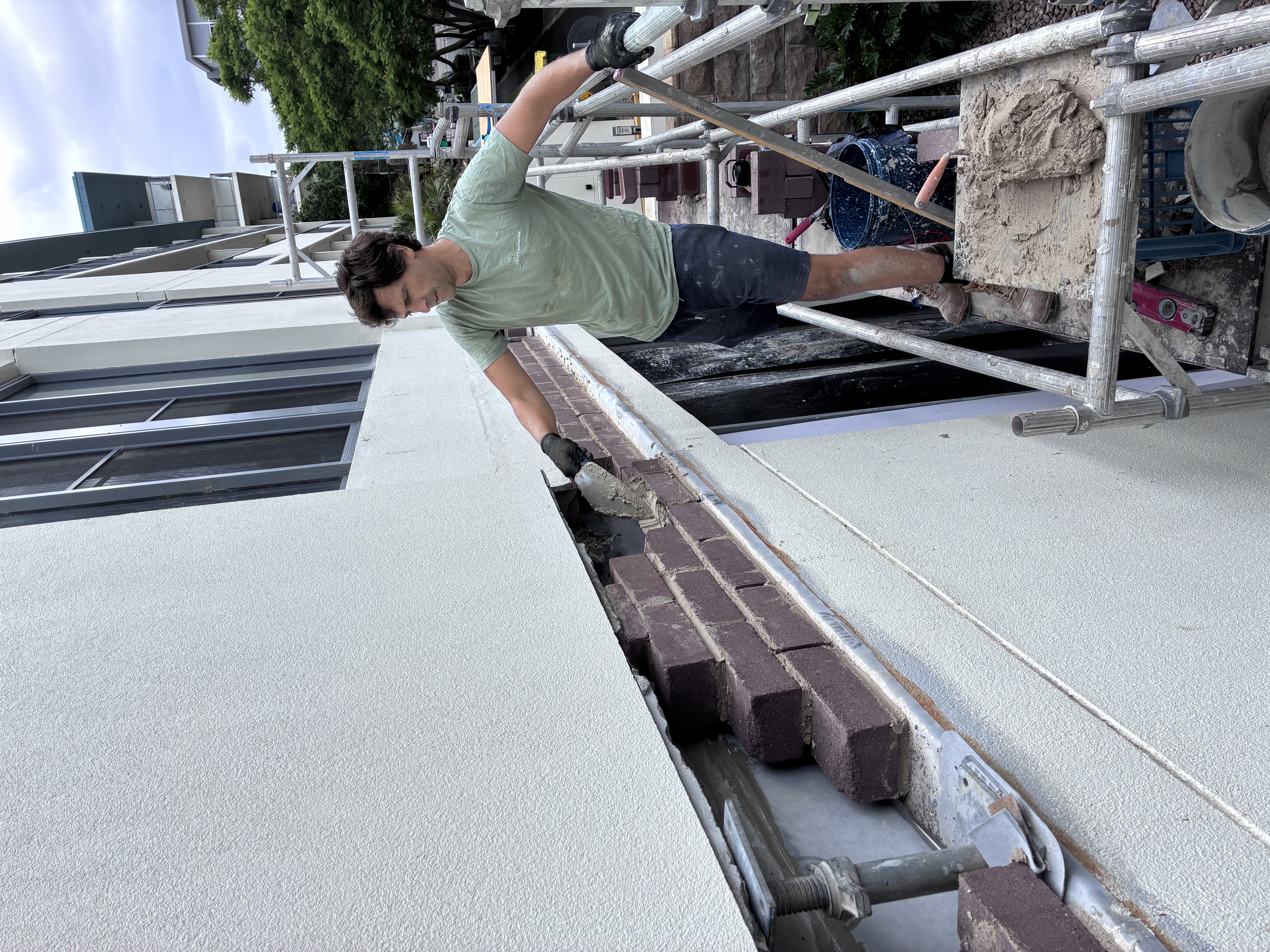 Aligning replacement soldier course bricks above a new parapet lintel during reinstatement